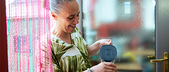 Woman standing in the doorway, pouring a glass of water and smiling