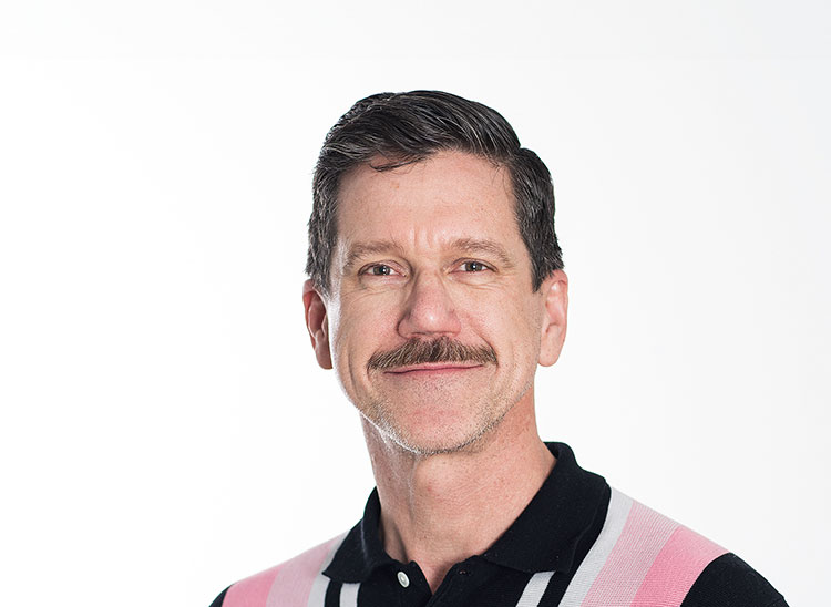 Tom Lawson  - dark hair, moustache and wearing black and pink striped shirt
