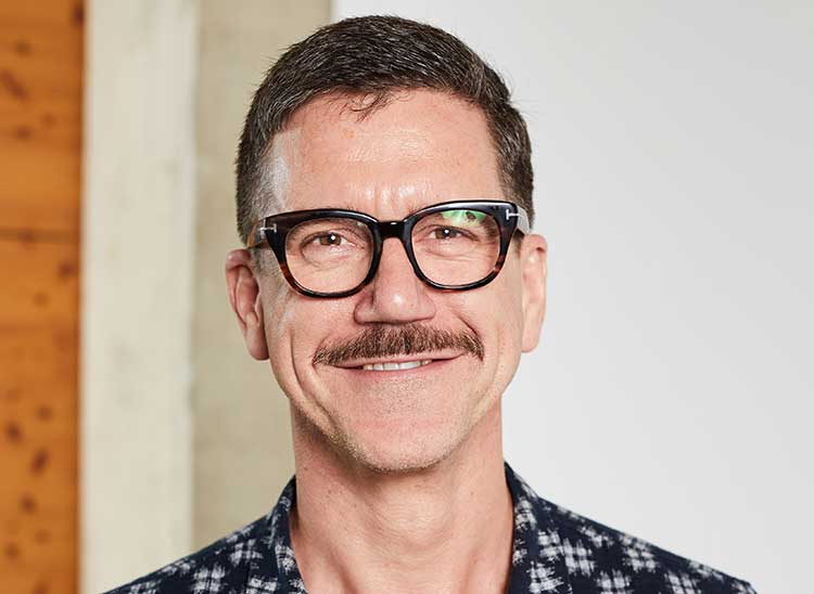 Thomas Lawson, CEO, Turn2us, wearing black glasses and blue shirt and smiling.