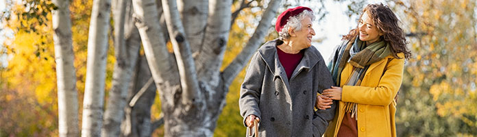 Older woman walking arm in arm with younger woman