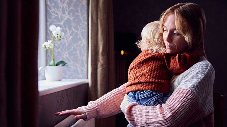 Mother cuddling child and holding hand over radiator