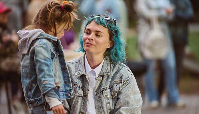 Mother kneeling down with daughter in street