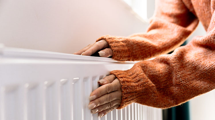 Woman holding her hands over a radiator