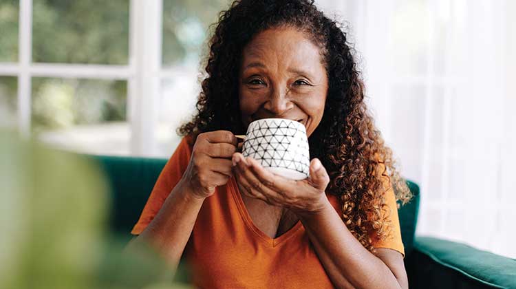 Smiling woman drinking from a mug and wearing orange t-shirt