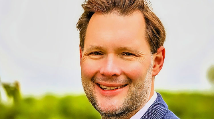 Matthew Wilkley with brown hair, smiling and wearing blue jacket