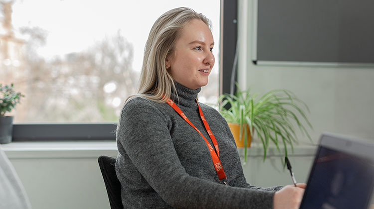 Woman with blonde hair sitting at desk with pen in hand
